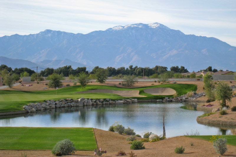 golf course hole with flag and community homes in the background with mountain range