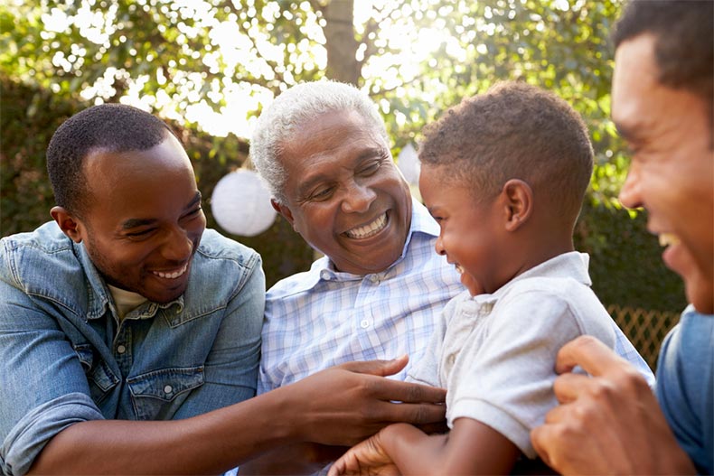 An older man laughing and smiling with his family