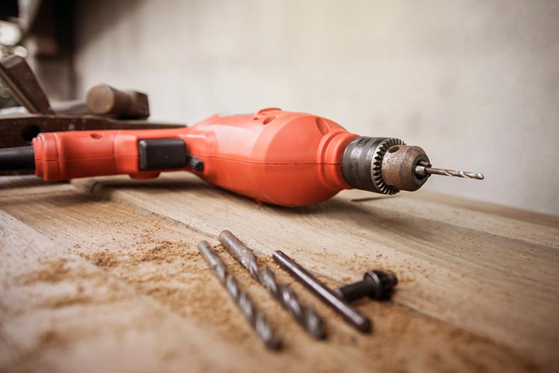 A drill and a set of drill bits on a wooden work table