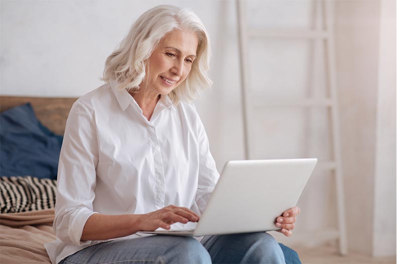 An older woman browsing listing photos on her laptop