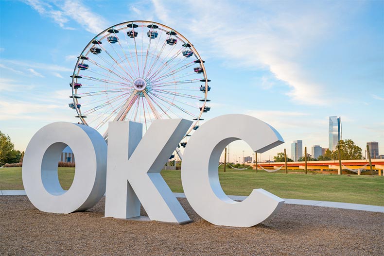 The OKC sign and ferris wheel with the Oklahoma City skyline in the background