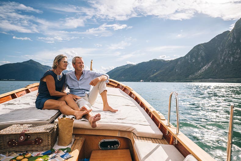 An older couple enjoys traveling on a boat through the mountains, made possible since they live in a maintenance-free community