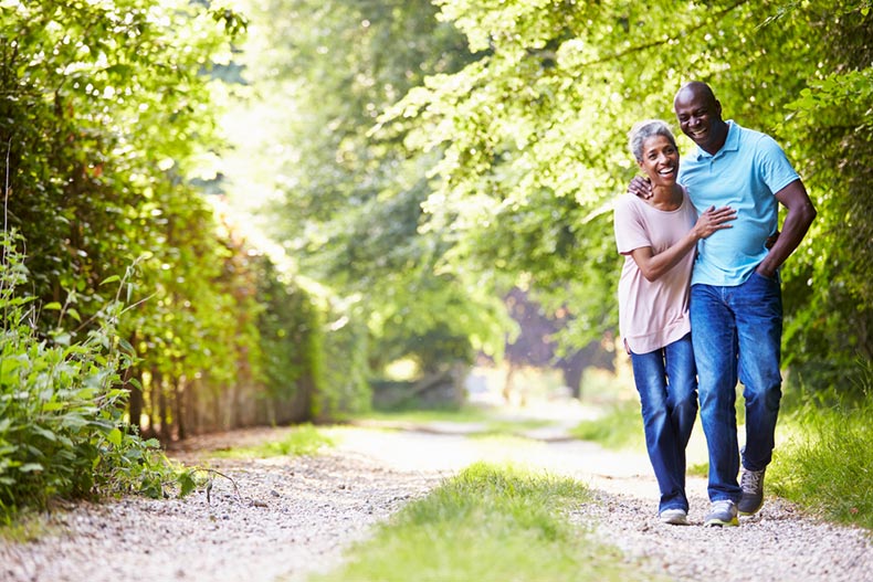 An older couple smiling while walking on a gravel path in their maintenance-free 55+ community