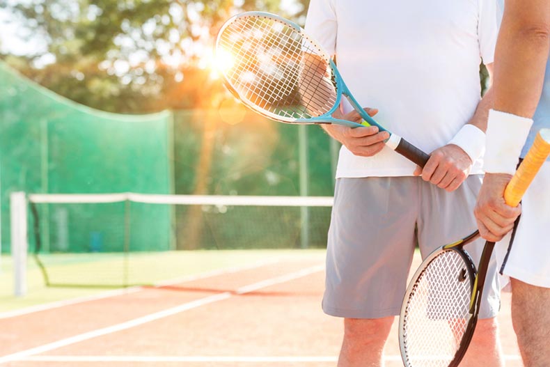 Two retired men on a tennis court in their 55+ community at sunset