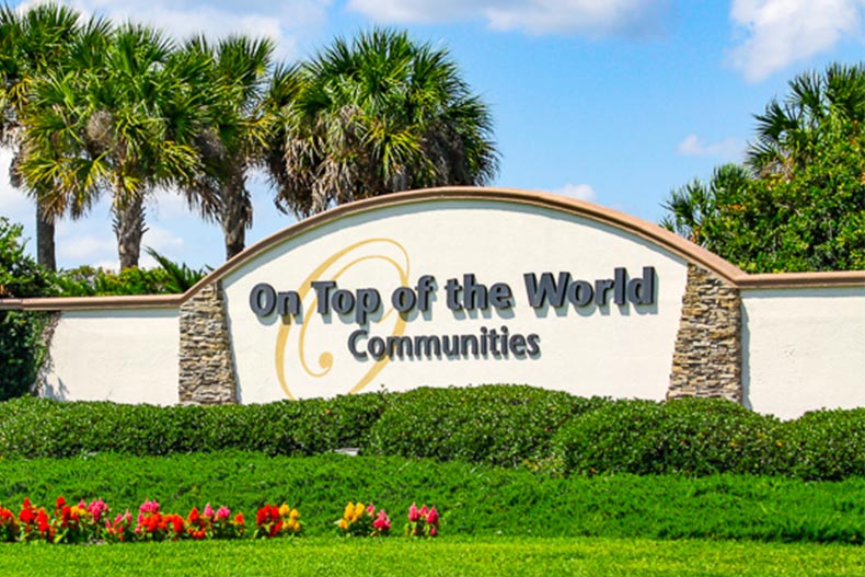 Palm trees and greenery surrounding the community sign for On Top of the World in Ocala, Florida