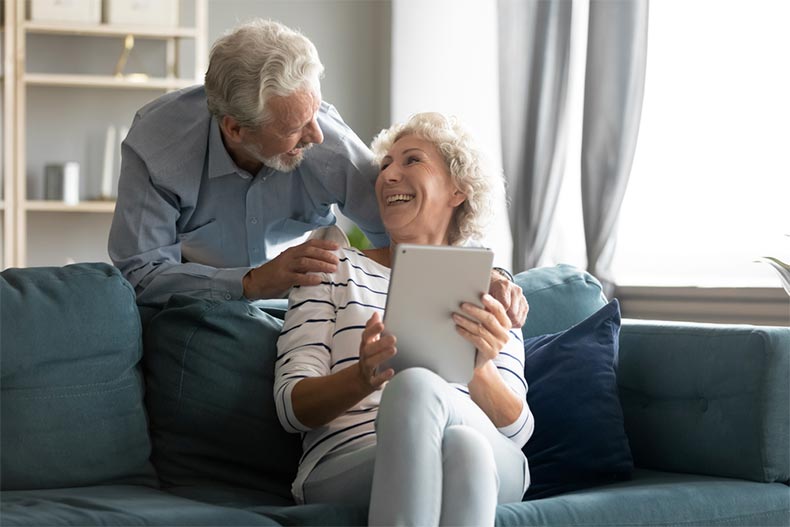 An excited older man and woman having fun with a computer tablet