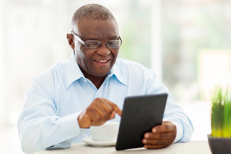 A cheerful senior man enjoying an online hobby on a tablet at home