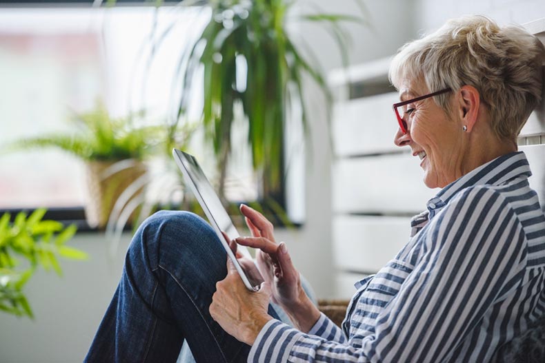 A senior woman using a digital tablet to find the value of her home