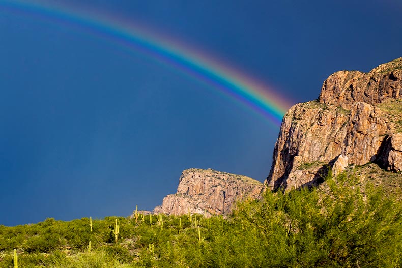 A rainbow in a stormy sky leading to Pusch Ridge in Oro Valley, Arizona
