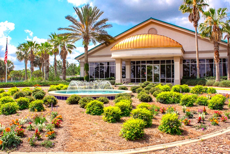 Exterior photo of the clubhouse at On Top of the World in Ocala, Florida with a fountain and garden in front