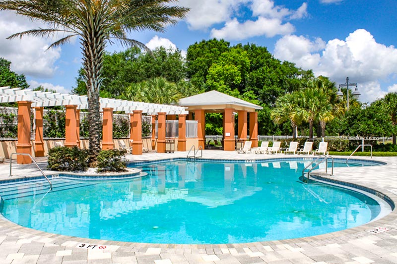 View of the outdoor pool and patio with cabanas at On Top of the World in Ocala, FL.