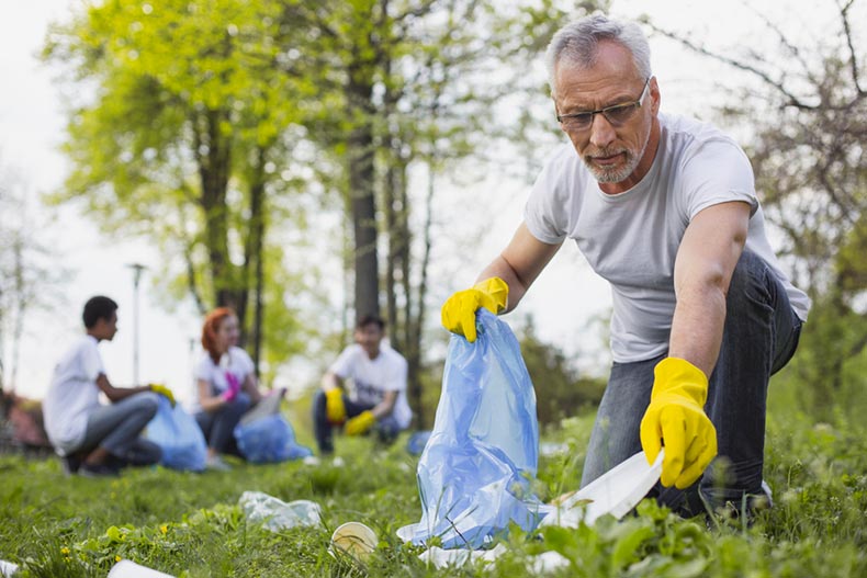 A senior volunteer collecting trash in a park