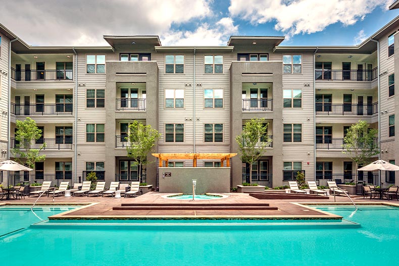 Exterior view of an apartment building in Overture Plano with a resort-style pool and spa in the foreground, located in Plano Texas