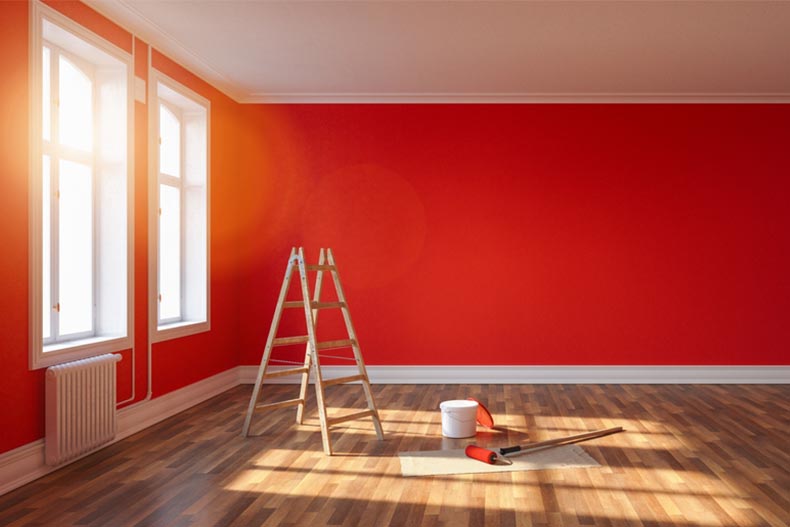 A red wall, a ladder, and a paint bucket in a detached condo after renovation