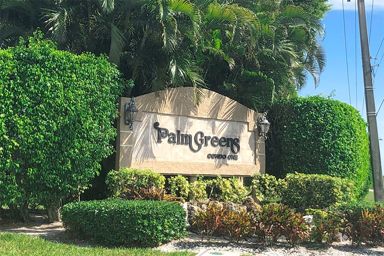 Greenery surrounding the community sign for Palm Greens in Delray Beach, Florida