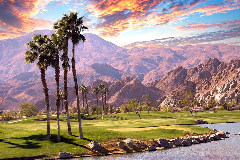 View of a golf course and pond in Palm Springs, California with mountains in the background