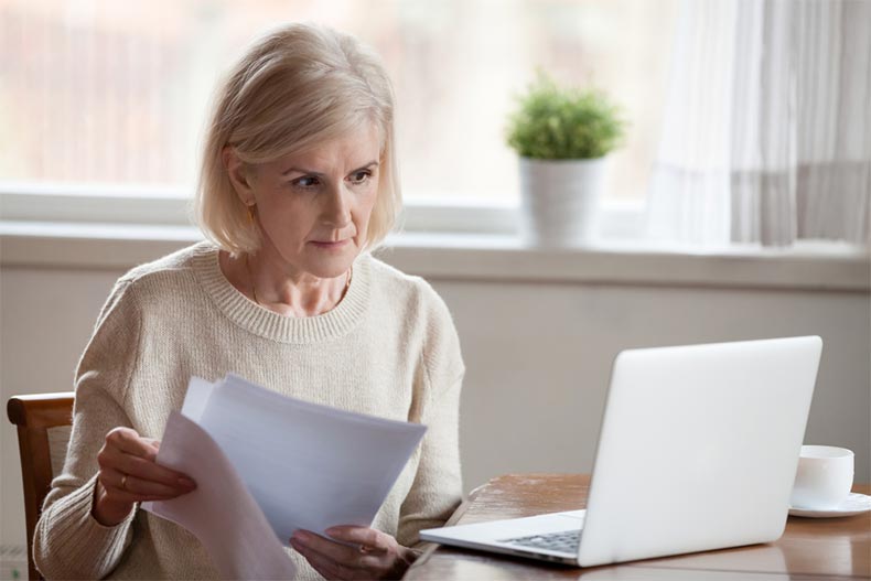 An active adult woman looking at her laptop while going through homebuying paperwork