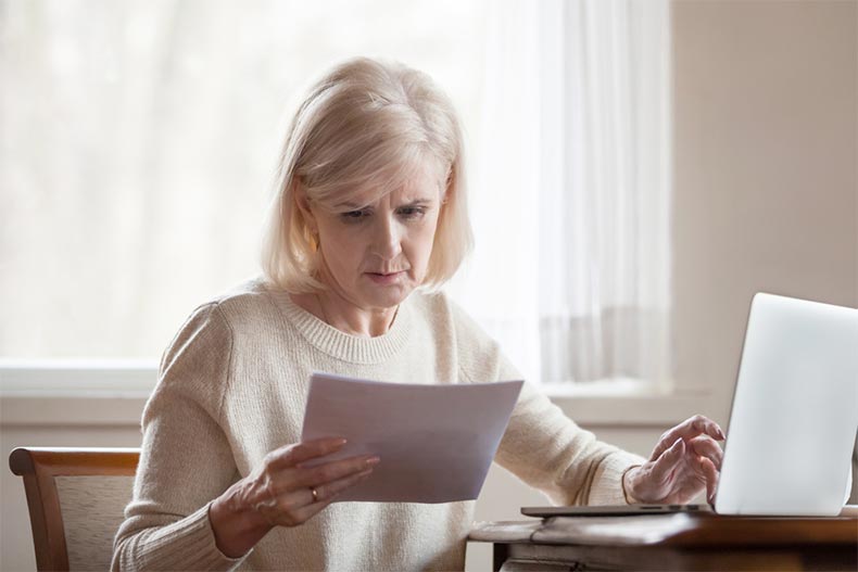 A senior woman looking over some paperwork with a serious expression