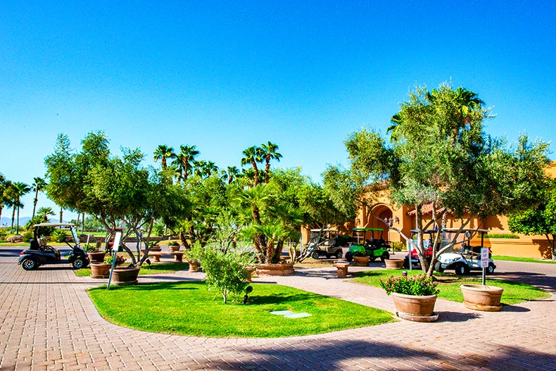 Several golf carts parked on a driveway surrounding a courtyard in PebbleCreek, located in Goodyear, Arizona