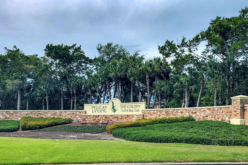 The beige stone entrance sign for Pelican Landing in Bonita Springs, Florida surrounding by trees and shrubbery