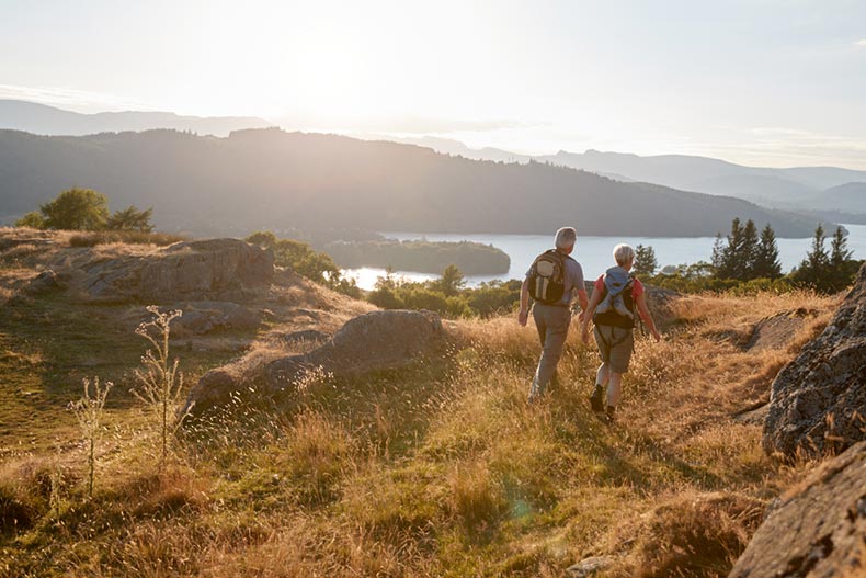 A senior couple walking along a trail beside a lake near their 55+ community