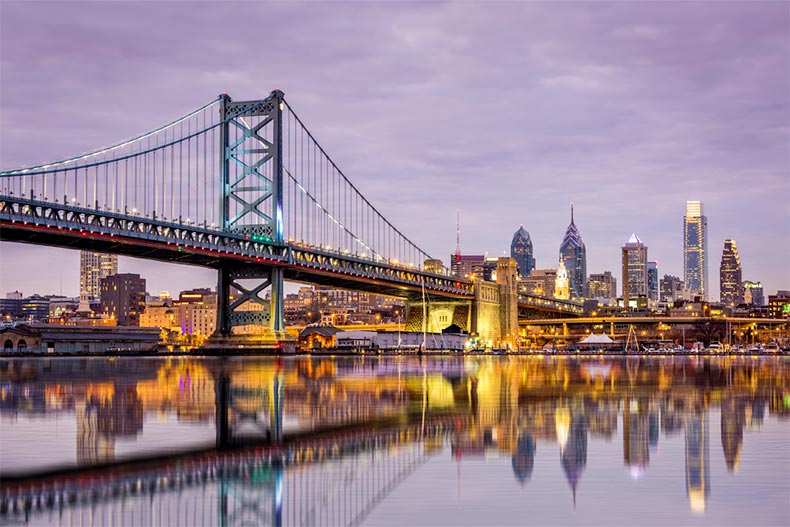 The Ben Franklin bridge and Philadelphia skyline reflected in the Delaware river at twilight