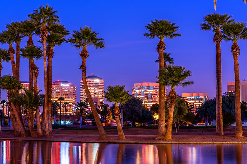 Phoenix, Arizona skyline viewed through palm trees in front of a lake in Encanto Park