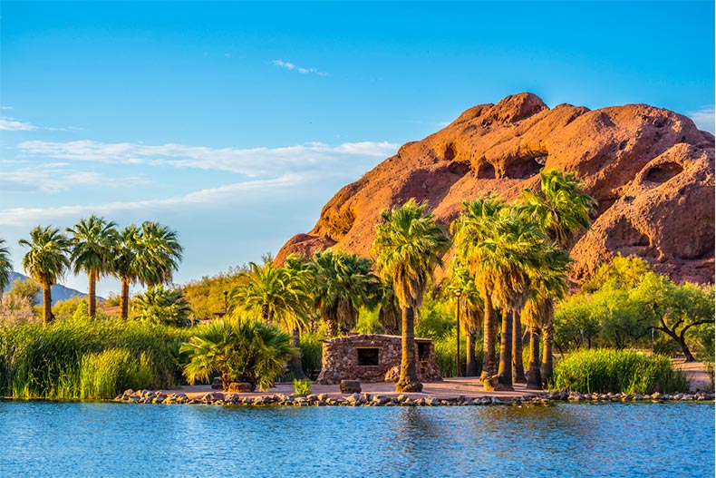 View of palm trees and a rocky hill across a body of water in Phoenix, Arizona