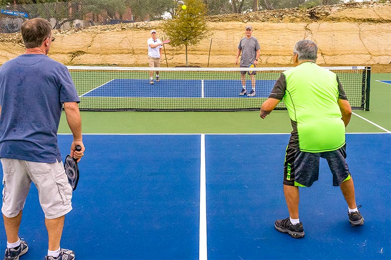 Four older adults playing pickleball on court in Kissing Tree, Texas