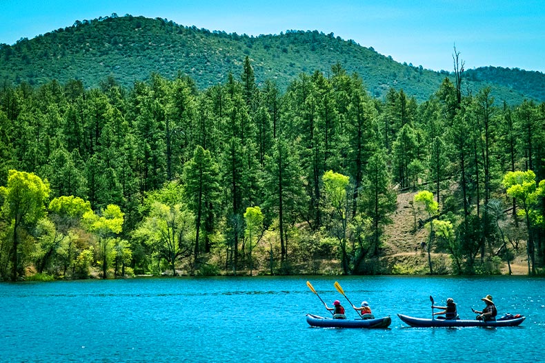 Four canoers on Lynx Lake in Prescott, Arizona with a forest covered mountain in the background