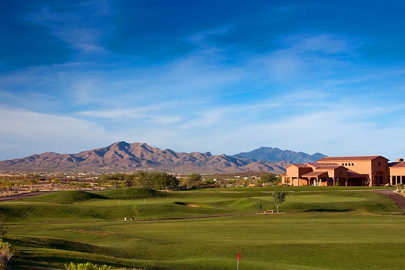 View of the golf course at Del Webb at Rancho del Lago with a clubhouse and mountain range in the background