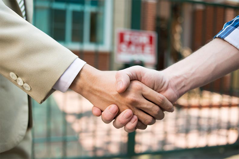 A real estate agent and a home seller shaking hands