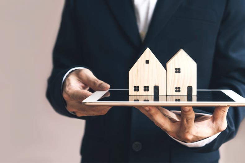 A Realtor holding a tablet with wooden model homes on top