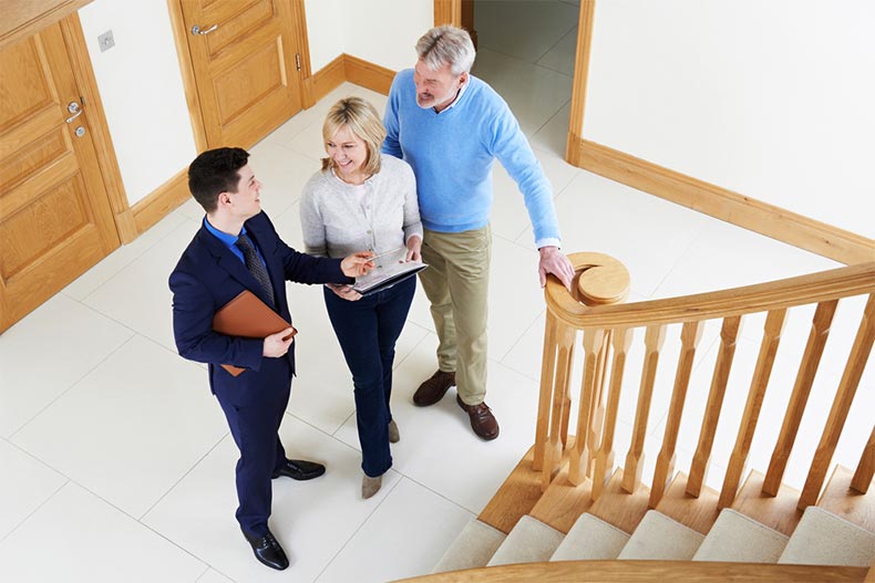 A realtor showing an active adult couple around a new construction house for sale