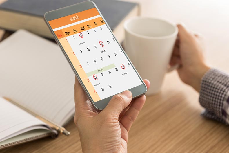 Closeup on a hand holding a smart phone that's displaying a calendar with important dates circled
