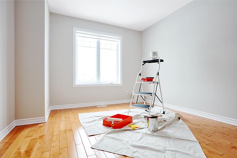 A tarp, a ladder, and painting supplies in a house being renovated