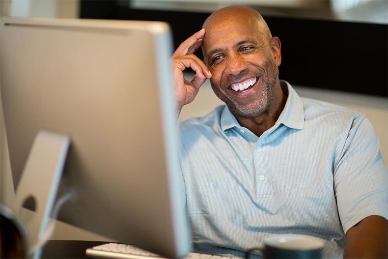 A retired man smiling while working from his home office