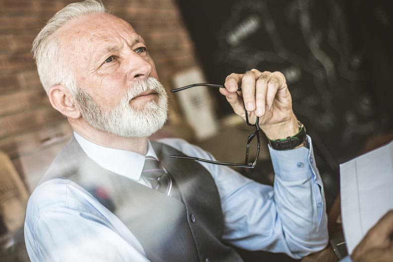 An older businessman pausing to think as he drafts a retirement notice