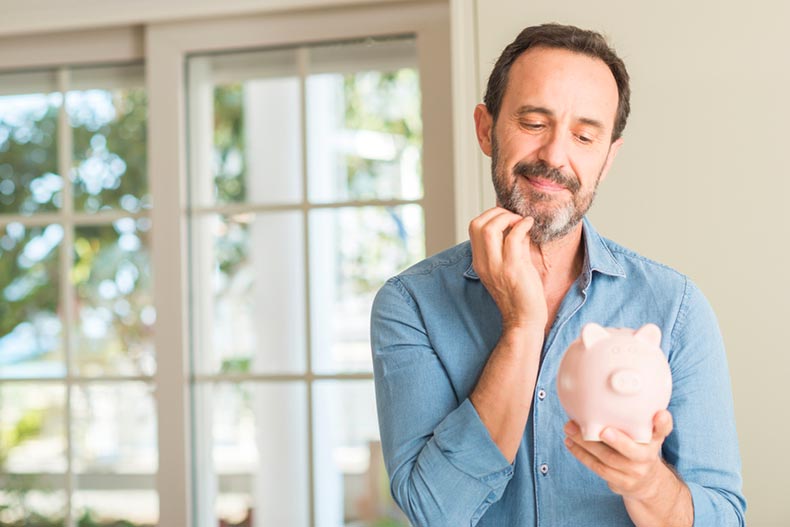 A middle-age man looking at a piggy bank and considering his savings