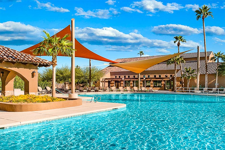 Lounge chairs on the patio surrounding the outdoor pool at Robson Ranch in Eloy, Arizona