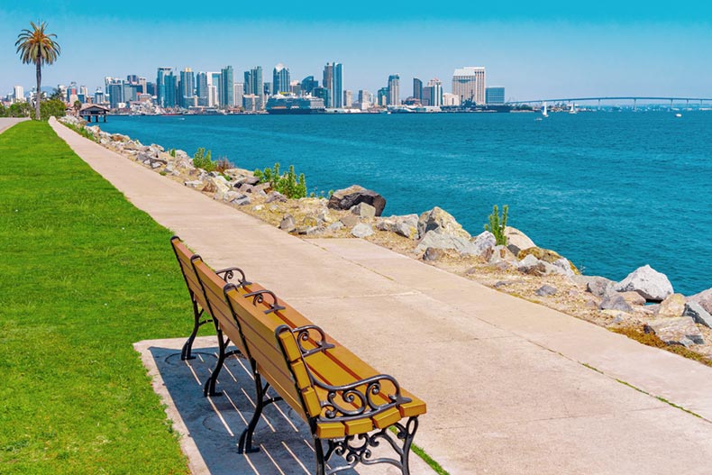 A bench along a sidewalk by the waterfront of San Diego near the Coronado Bay Bridge