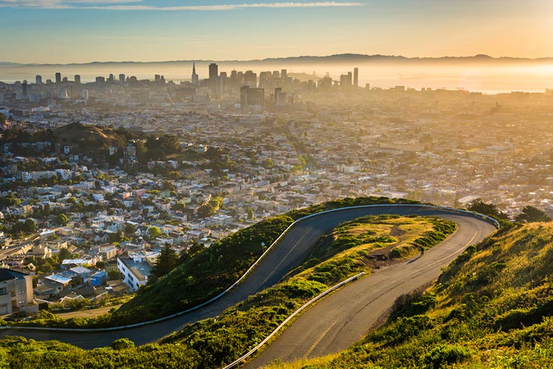 A curvy road and view of downtown at sunrise from Twin Peaks in San Francisco, California