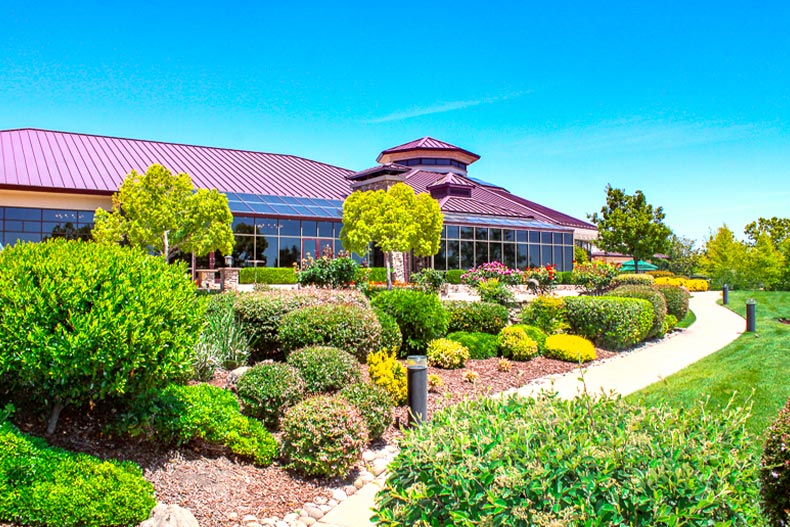 Exterior photo of the clubhouse in Sun City Lincoln Hills surrounding by shrubbery and a sidewalk