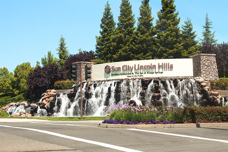 Photo of the Sun City Lincoln Hills entrance sign above a stone waterfall in Lincoln, California