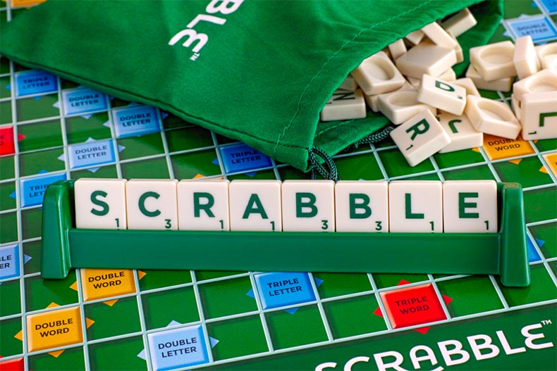 Close up on a board of Scrabble with tile pieces spelling Scrabble