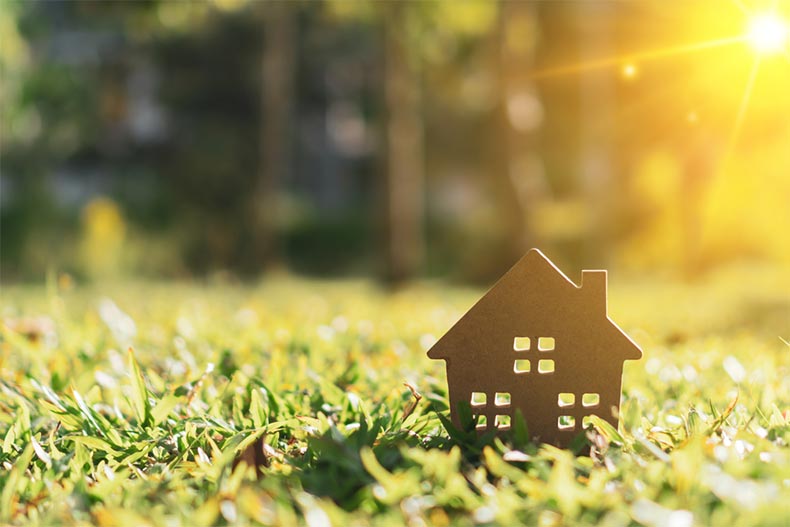 Close up on a tiny home model on green grass with sunlight in the background