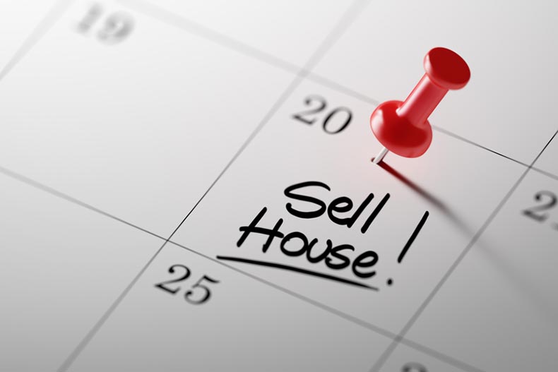 A calendar with a red push pin on the date marked "Sell House!"