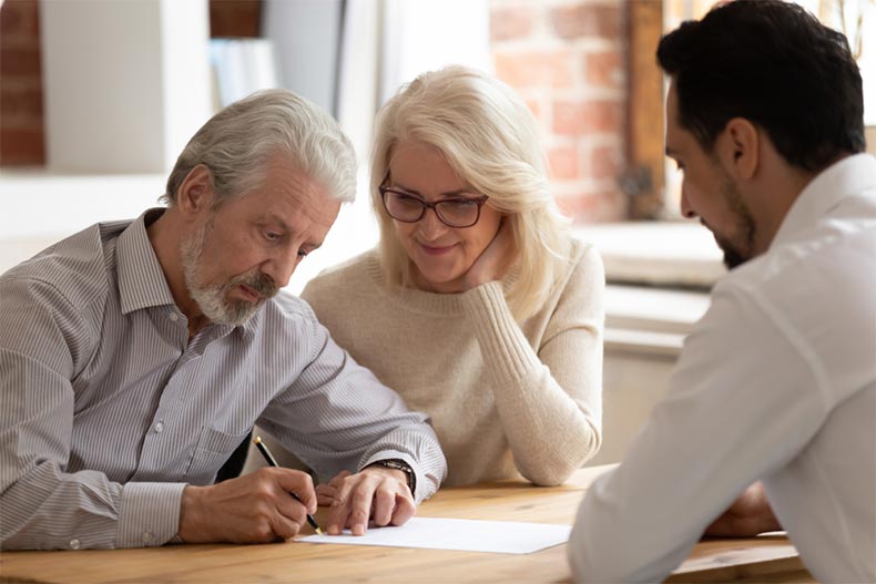 A senior couple signing a contract with their real estate agent