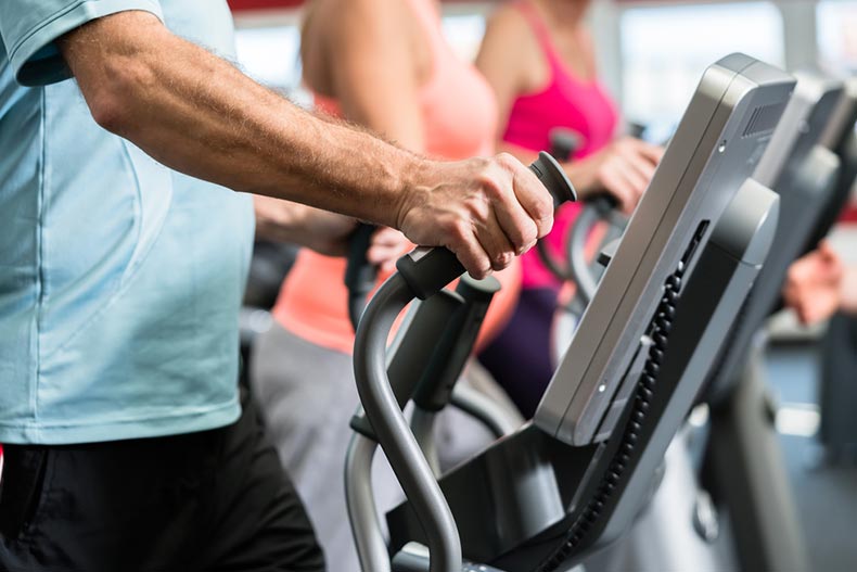 Active adults working out on cardio equipment in a fitness center