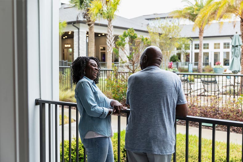 Smiling couple enjoys time on their porch in their 55+ community